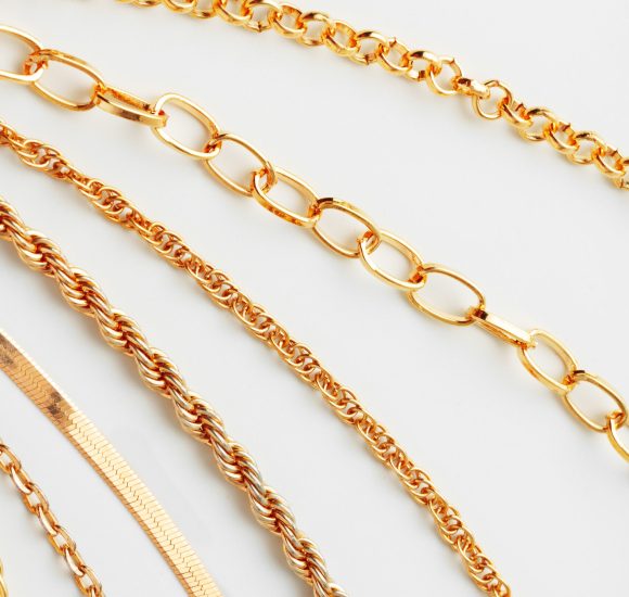 Jewelry set of golden chains on the white background close up